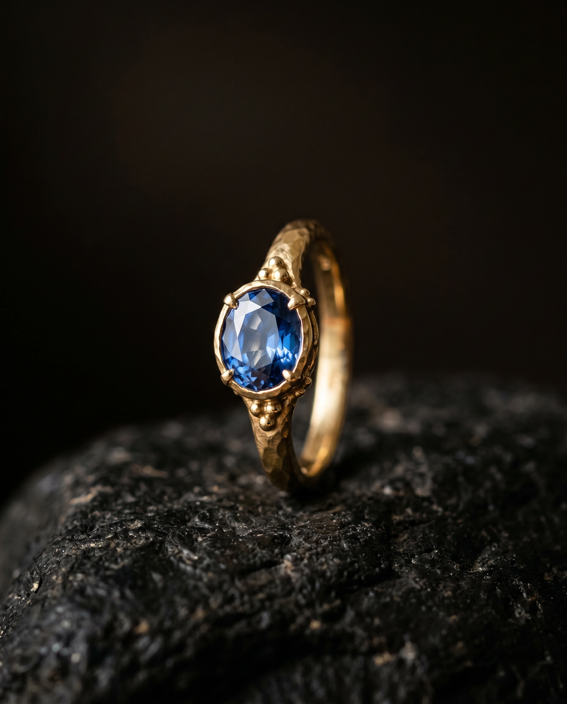 Handgemaakte gouden ring met edelsteen tegen een donkere achtergrond